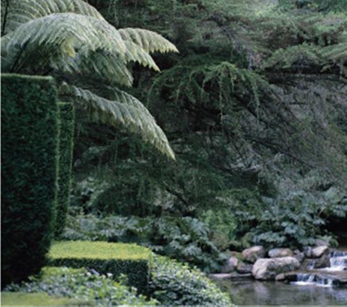 a picture of a garden with a river and trees at Huka Lodge in Taupo