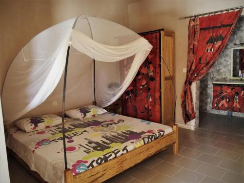 a bedroom with a bed with a canopy at Auberge Keur Ely in Ouoran