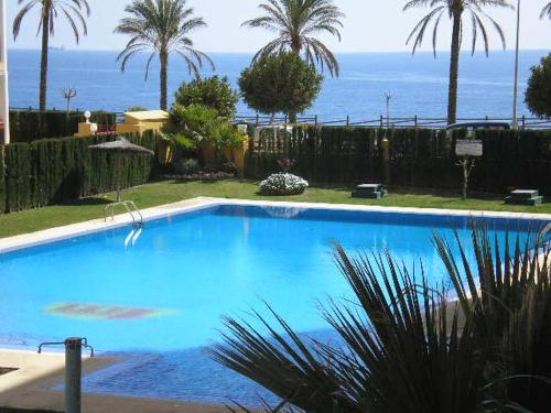 ein großer blauer Pool mit dem Ozean im Hintergrund in der Unterkunft Apartamento Frente Al Mar in Villajoyosa