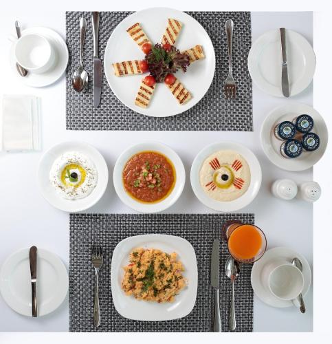 a table with white plates of food and silverware at Novotel Jazan in Jazan