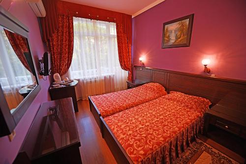 Dormitorio rojo con cama y ventana en Katran Hotel, en Lazarevskoye
