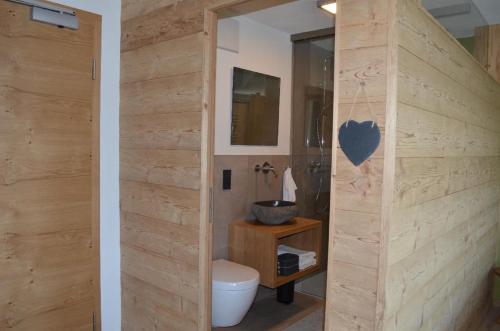 een badkamer met een toilet en een houten muur bij Die Herberge in Mauth