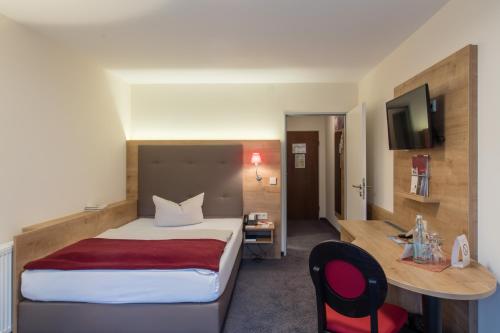 a hotel room with a large bed and a desk at Hotel St. Georg in Bad Aibling