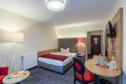 a hotel room with a bed and a table and chairs at Hotel St. Georg in Bad Aibling