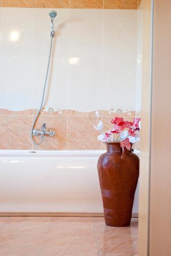 a brown vase with flowers in front of a bath tub at Pensiunea Vlad in Timişoara