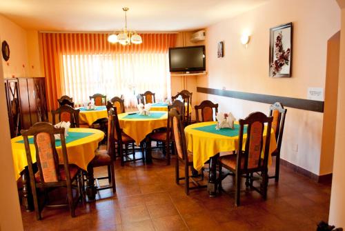 a dining room with tables and chairs with yellow table cloths at Pensiunea Vlad in Timişoara