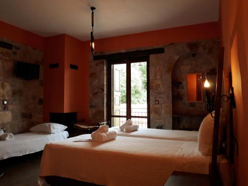 2 letti in una camera con pareti arancioni e finestra di Messana a Messini