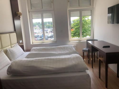 a bedroom with two beds and a desk and two windows at Ostsee Hotel Travemünde in Travemünde
