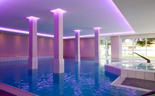 a swimming pool in a building with purple lighting at Hotel St. Georg in Bad Aibling