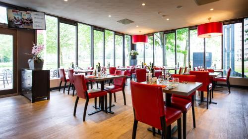 a restaurant with red chairs and tables and windows at Bastion Hotel Leiden Voorschoten in Leiden
