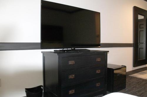 a living room with a tv on a dresser with a dresser at The Craftsman Inn & Suites in Fayetteville