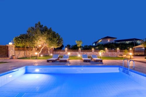 a swimming pool at night with lounge chairs and a pool at Iguana Villa in Kalamaki