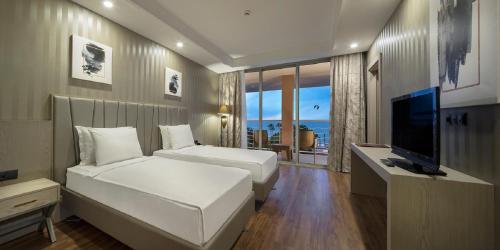 a bedroom with two beds and a flat screen tv at Kilikya Palace Goynuk in Kemer