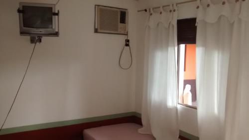 a small room with a window and a television at Pousada Enseada do Coqueiro in Guarapari