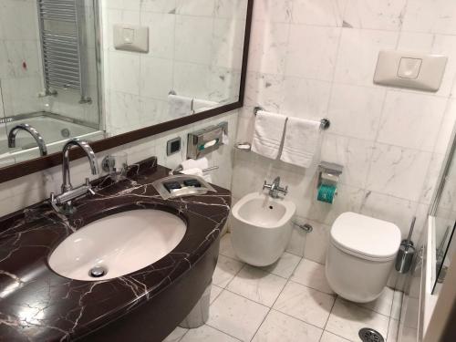 a bathroom with a sink and a toilet and a mirror at Italiana Hotels Cosenza in Cosenza