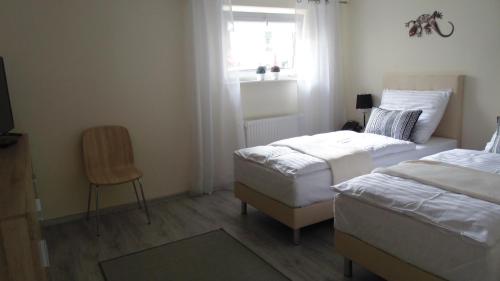 シフィノウイシチェにあるApartamenty Cudowna Wyspaのベッドルーム1室(ベッド2台、椅子、窓付)