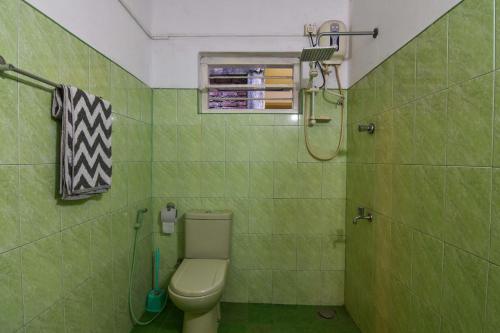 a green bathroom with a toilet and a shower at Ceylon Boutique Homestay Kandy in Kandy