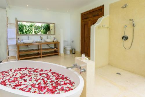 a bathroom with a bath tub filled with flowers at Hevea Villas in Seminyak
