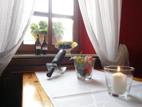 a table with a candle and wine bottles and a window at Weingasthof Zum weißen Roß in Osthofen