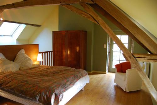 a bedroom with a large bed and a chair at La Tour in Marcilly-la-Gueurce