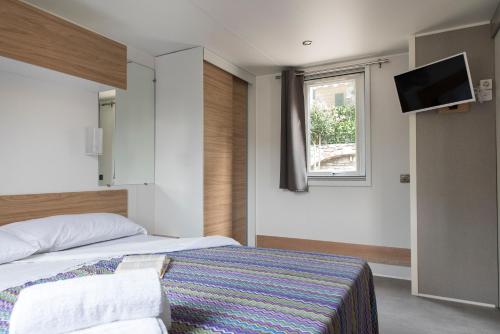 ein Schlafzimmer mit einem Bett und einem Fernseher an der Wand in der Unterkunft Camping Edy in Diano Marina