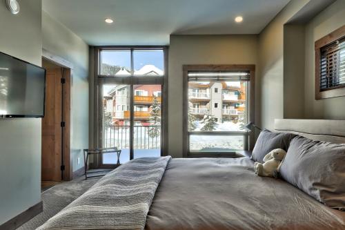 un osito de peluche sentado en una cama en un dormitorio en Village Walk Sun Peaks, en Sun Peaks