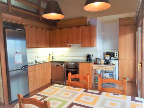 una cocina con armarios de madera y electrodomésticos de acero inoxidable en Apartamento Mirador Del Puigmal en Puigcerdá