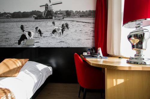 una camera d'albergo con scrivania, letto e tavolo con mucche di Bastion Hotel Leiden Oegstgeest a Oegstgeest