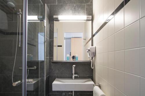 a bathroom with a sink and a mirror at Bastion Hotel Leiden Oegstgeest in Oegstgeest