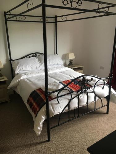a black metal bed with white sheets and pillows at Bishop Percys House in Bridgnorth