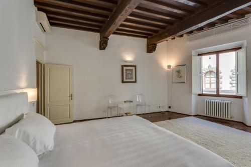 a white bedroom with a large bed and a window at Palazzo Tempi in San Casciano in Val di Pesa