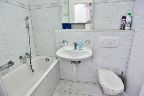 a bathroom with a sink and a toilet and a tub at Haus Flumser-Hockli - CharmingStay in Flumserberg