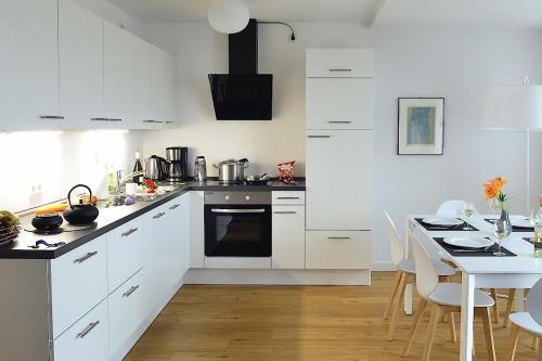 a kitchen with white cabinets and a table with chairs at Tor zum Meer in Helgoland
