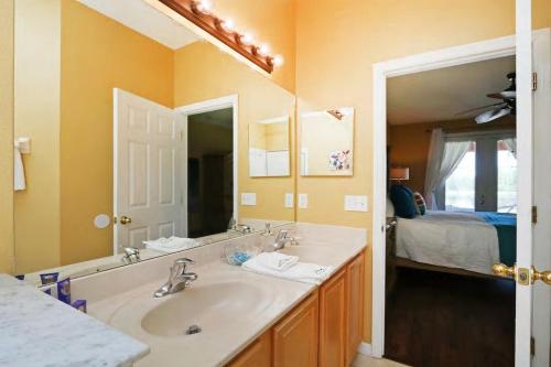 a bathroom with a sink and a mirror and a bed at Aquamarine Hideaway in Kissimmee