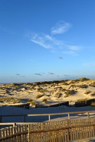 a wooden fence in front of a sandy beach at Pousada da Ria in Torreira