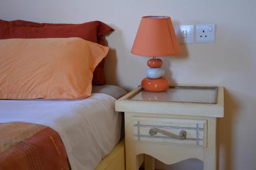 a bedroom with a bed and a lamp on a night stand at La Maison Soleil in Trou dʼ Eau Douce