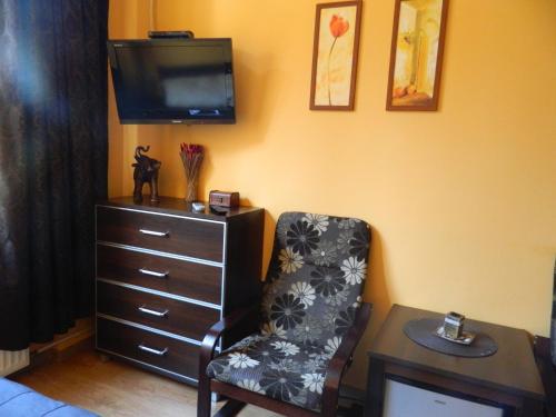 a bedroom with a chair and a dresser with a tv at Pokoje Integro in Szczecin