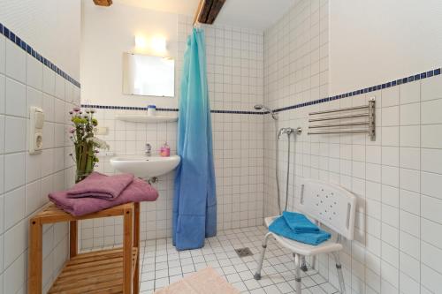 a white tiled bathroom with a sink and a shower at Ferienhaus "Zur Ottendorfer Hütte" in Ottendorf