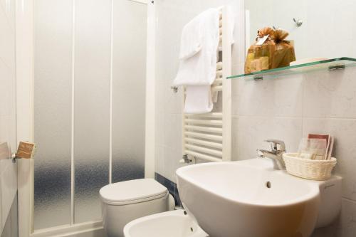 a white bathroom with a toilet and a sink at Hotel Montreal in Florence