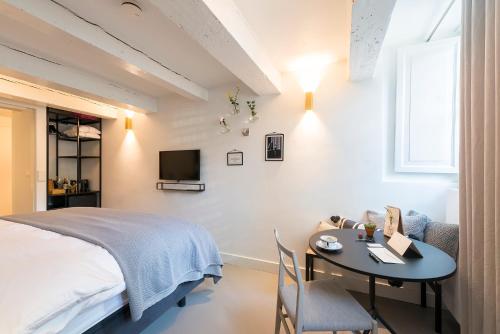a bedroom with a bed and a table and a tv at Milkhouse Luxury Stay Amsterdam in Amsterdam