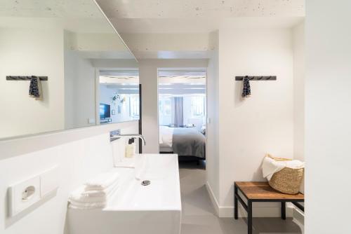 a white bathroom with a sink and a bedroom at Milkhouse Luxury Stay Amsterdam in Amsterdam