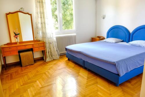 um quarto com uma cama azul, uma cómoda e um espelho em Chalandri Home Away em Atenas