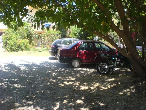 a car parked next to a motorcycle under a tree at Leonidas Rooms in Plataniás