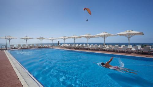 a person swimming in a swimming pool at a resort at Island Luxurious Suites Hotel and Spa- By Saida Hotels in Netanya