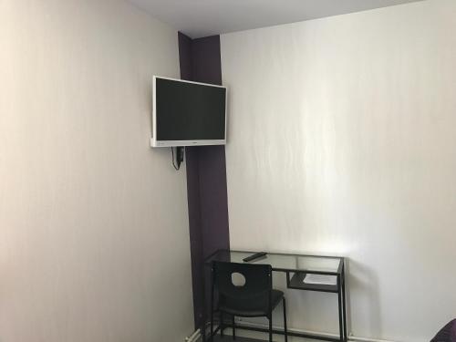a room with a table and a tv on a wall at Hotel de la Gare in Saint-Mihiel