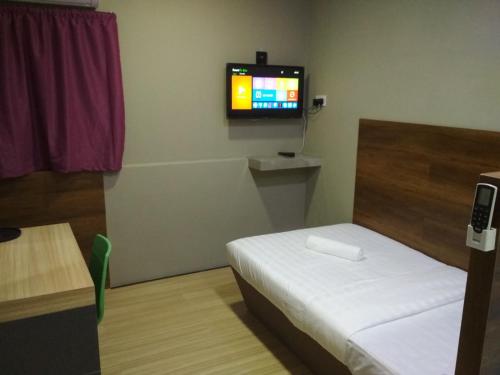 Qing Yun Rest House Gadong, Brunei Darussalam في بندر سيري بيغاوان: غرفة صغيرة بها سرير وتلفزيون على الحائط