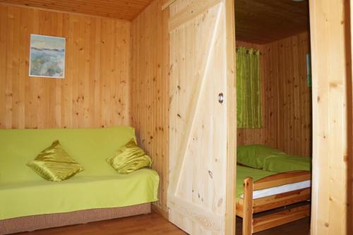 a room with a green couch in a wooden cabin at Domki Muszelka in Stegna