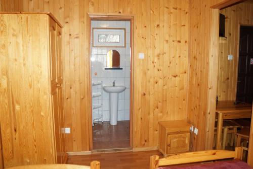 a bathroom with a sink in a wooden wall at Domki Muszelka in Stegna
