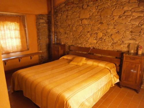 een slaapkamer met een bed en een stenen muur bij La cascina di Anna in Beverino