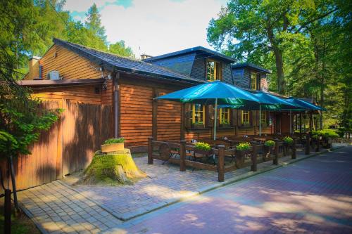 a house with benches and umbrellas in front of it at Wioska Indiańska River Park Zator SPA RESORT in Zator